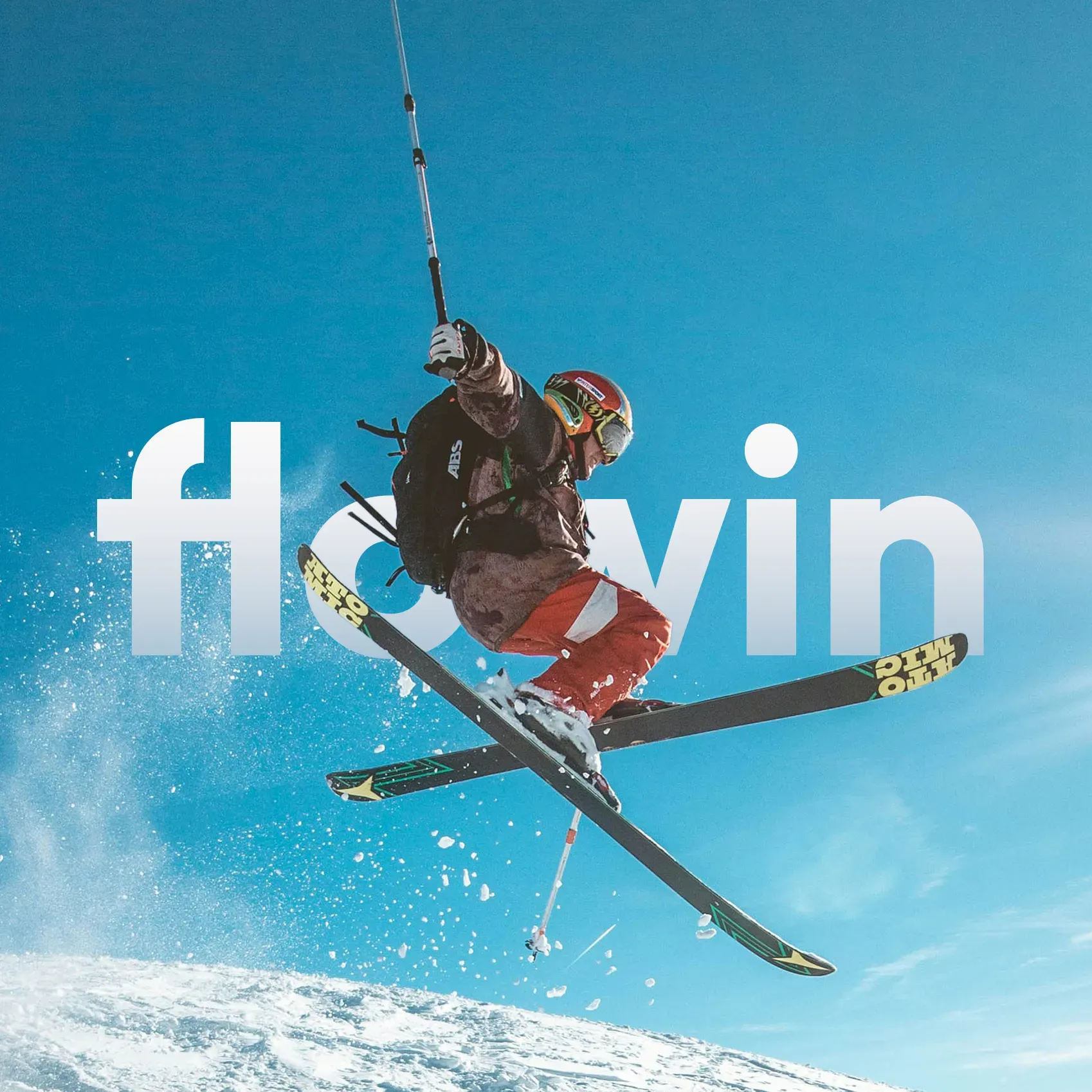 Person in der Luft auf Ski mit Flowin Schriftzug im Hintergrund